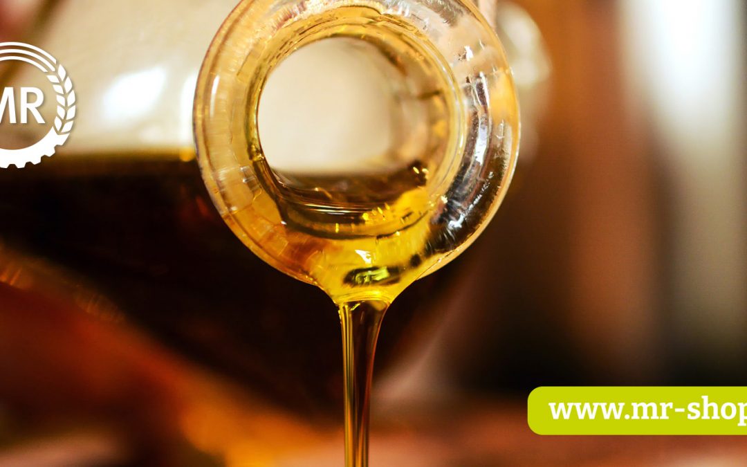 Goldenes Öl wird aus einer Glasflasche ausgeschüttet