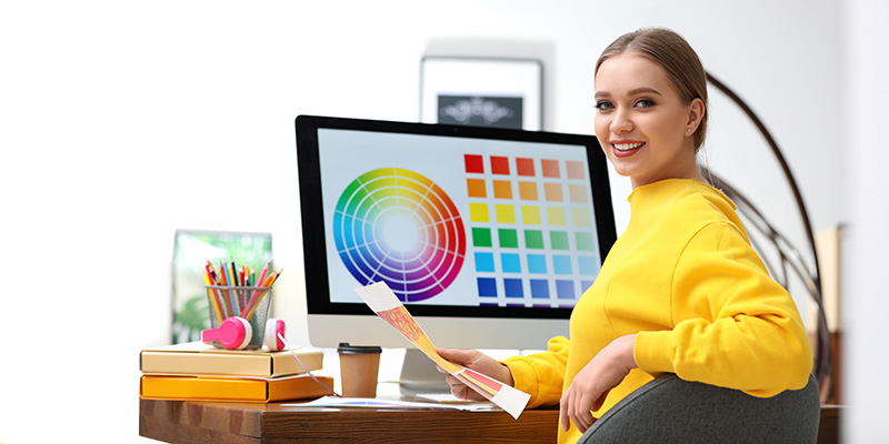Mediengestalterin vor PC mit Farbpalette